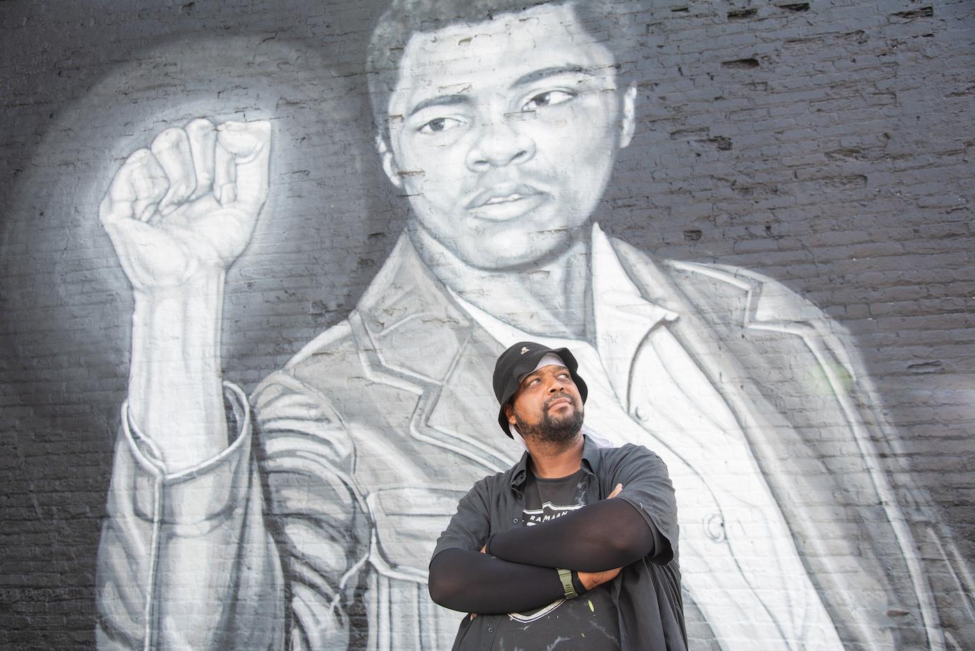 Rahmaan Statik poses in front of his Muhammad Ali mural in Chicago's Little Village. Photo: WTTW/Liz Markel