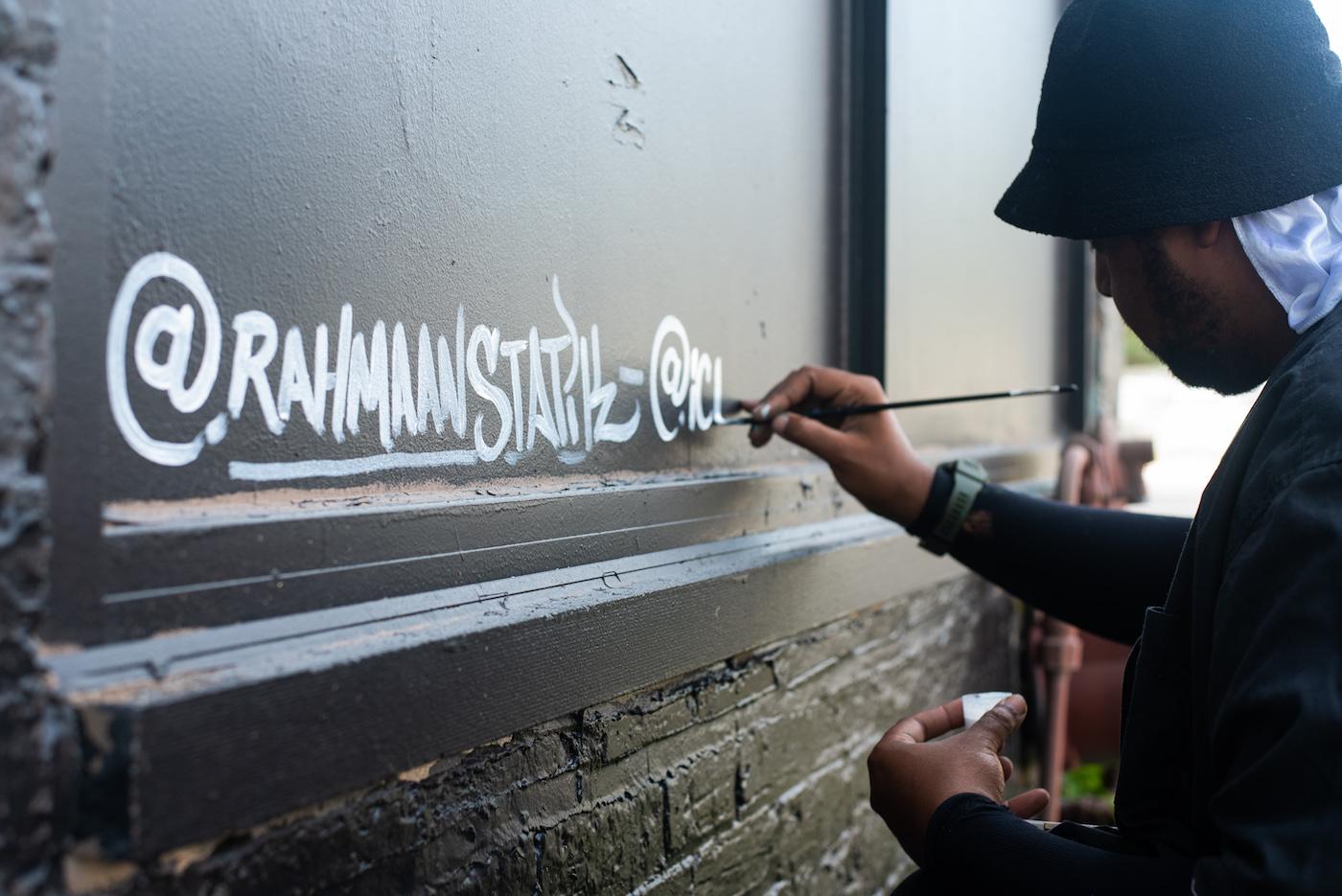 Rahmaan Statik signing his name on his Muhammad Ali mural in Chicago's Little Village. Photo: WTTW/Liz Markel