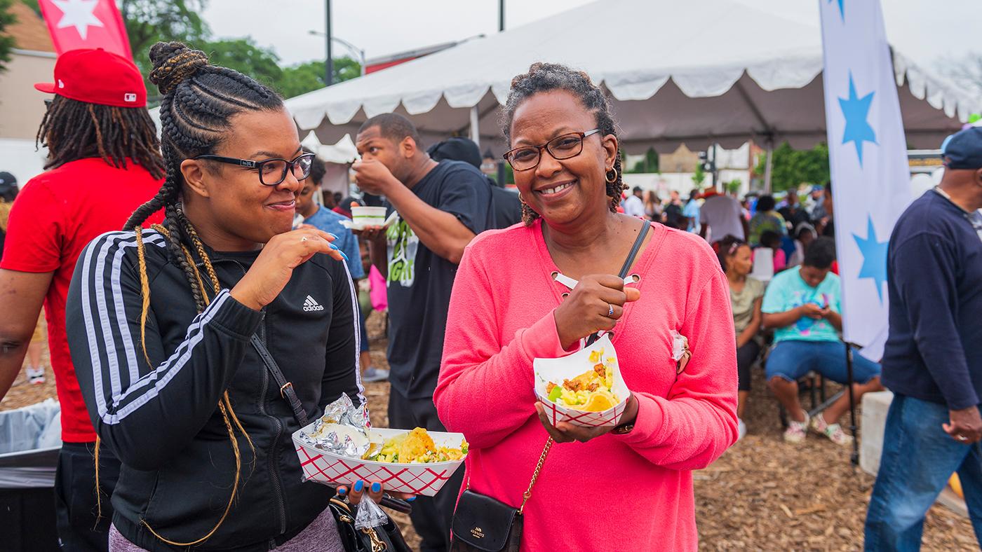 Two women smiling and eating food at the Taste of Chicago. Credit: City of Chicago DCASE