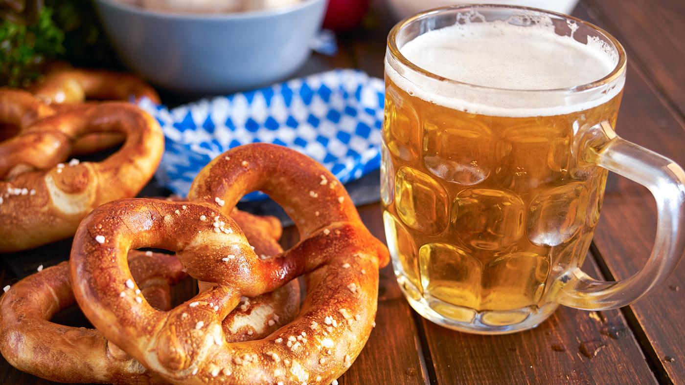 Soft pretzels on a table next to a glass beer stein