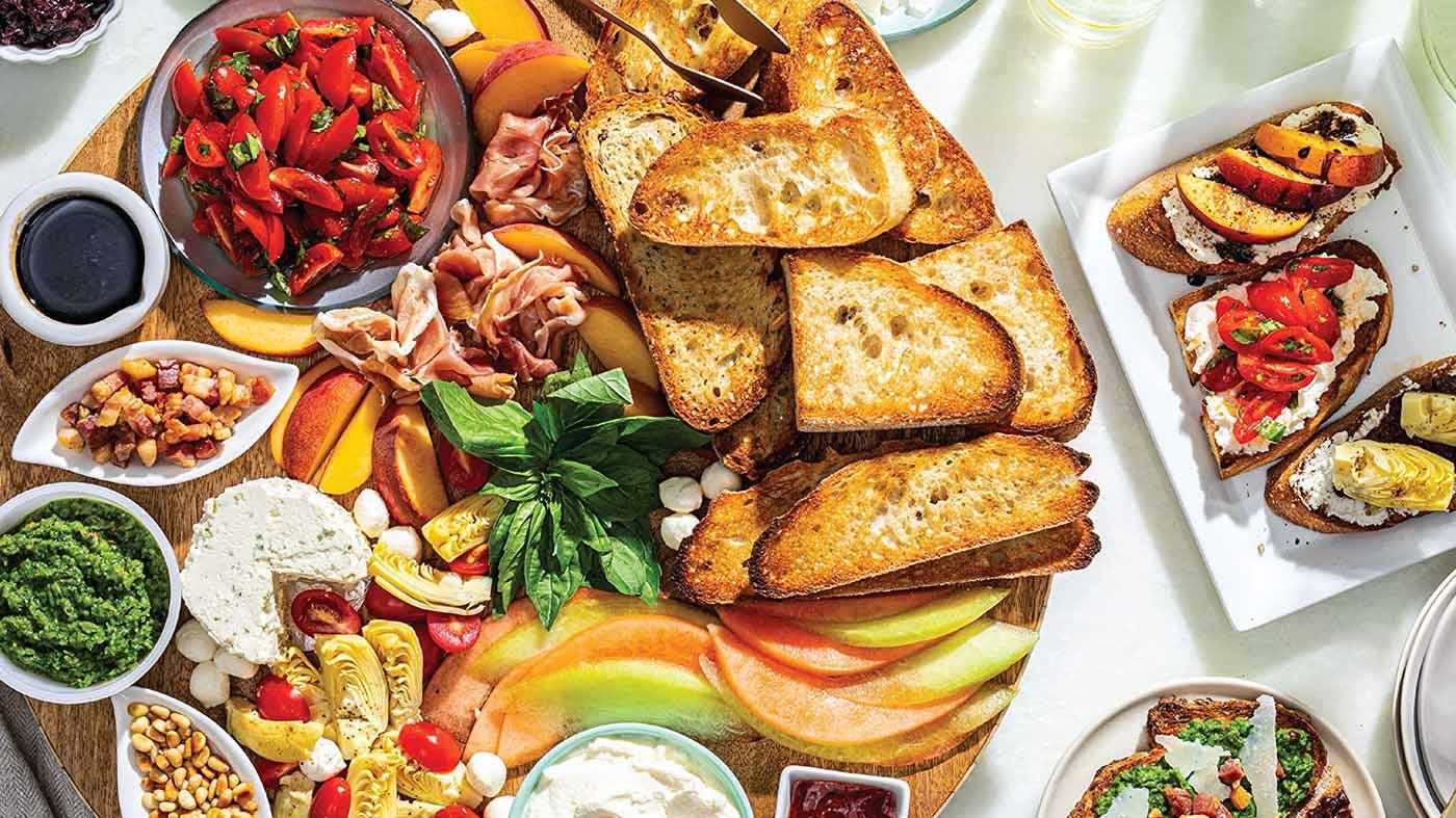 Bread, vegetables, cheeses, and spreads on a plate.