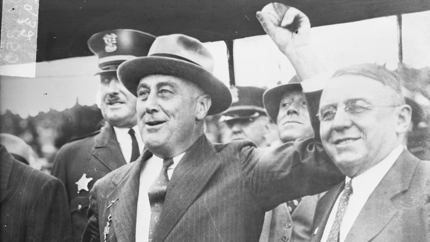 FDR stands next to Chicago mayor Anton Cermak, holding his hand up