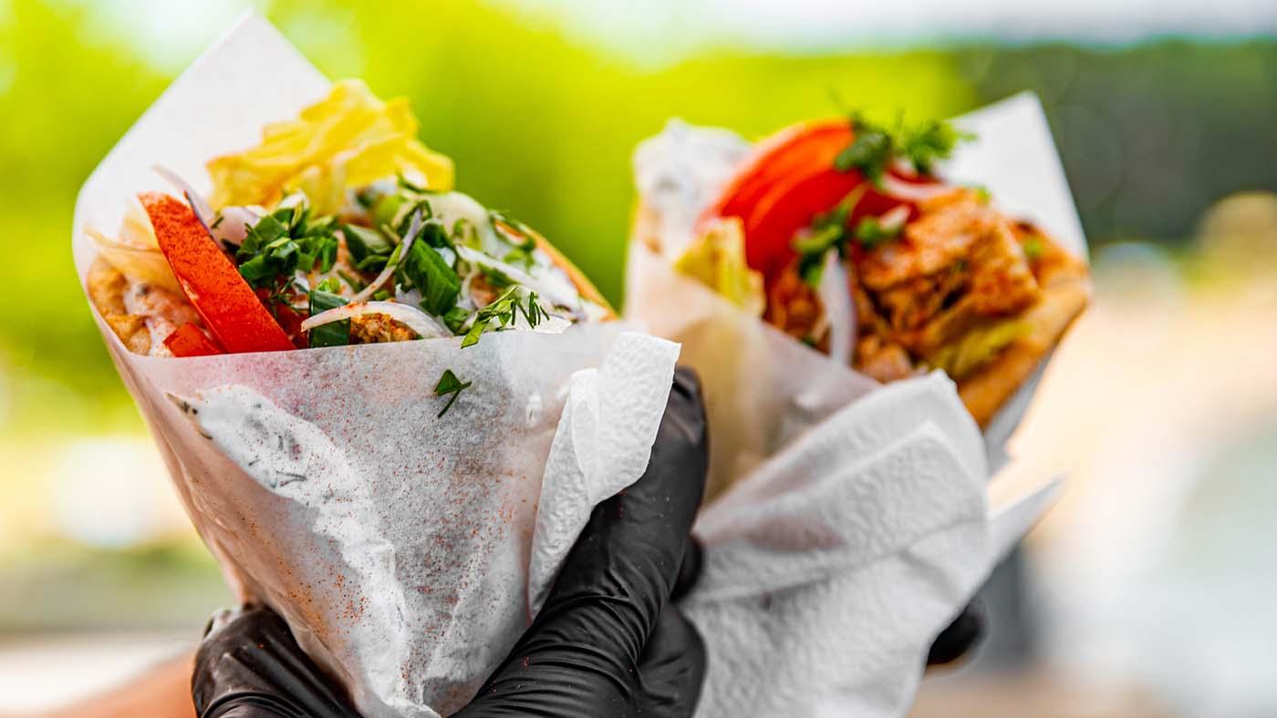 Two gyros being held up by a hand