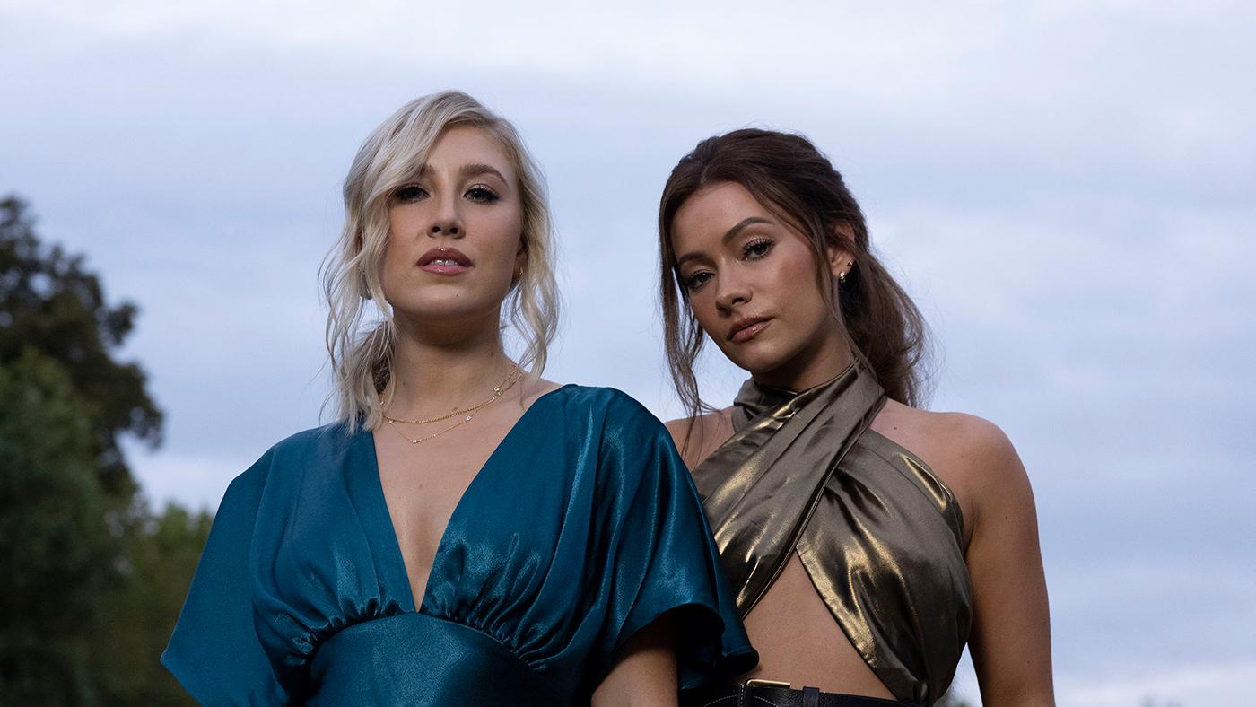 Maddie and Tae stand outside in a portrait