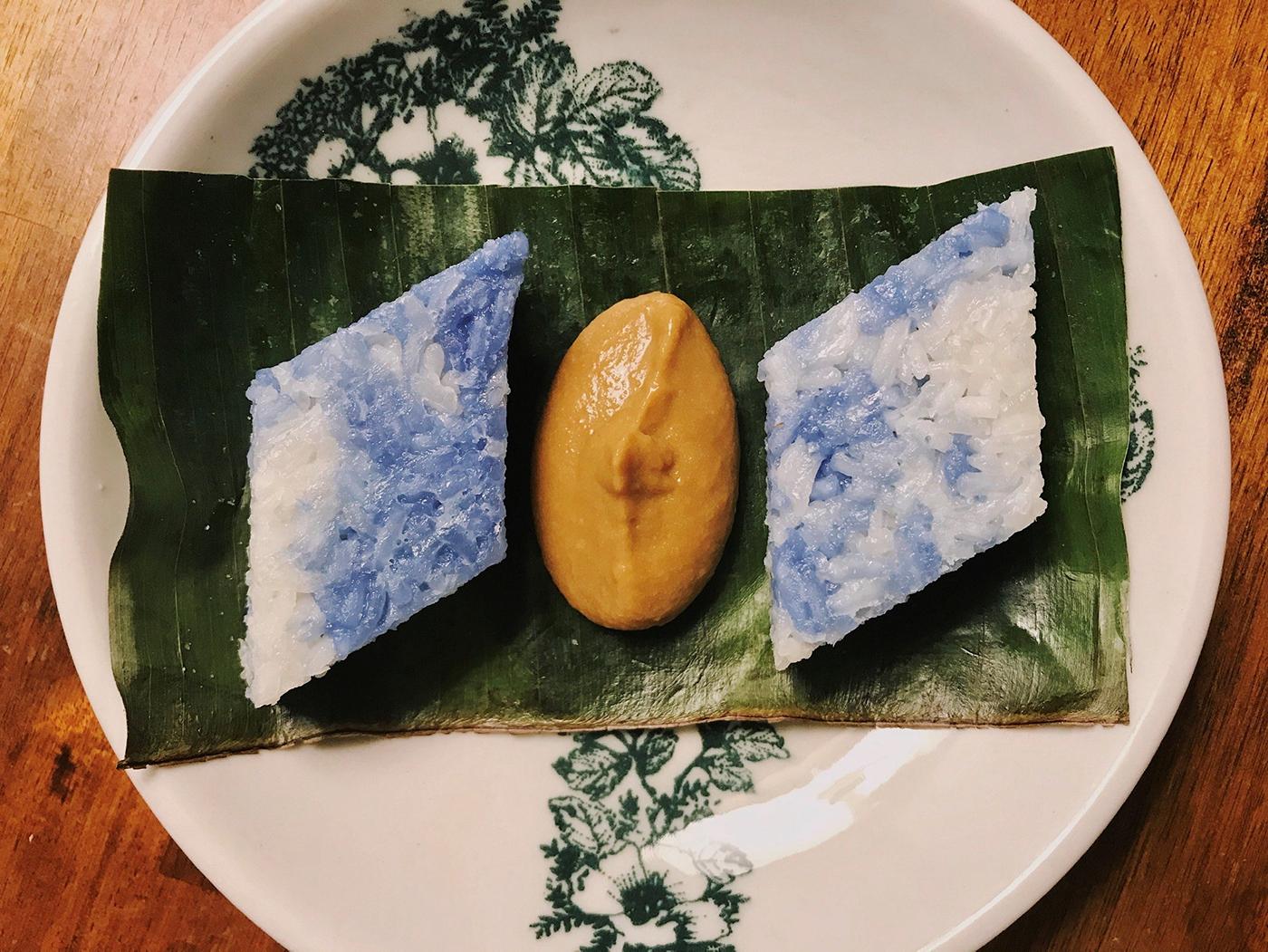 Two pieces of the Malaysian dessert kuih pulut tai tai on a banana leaf on a plate with kaya jam in the middle