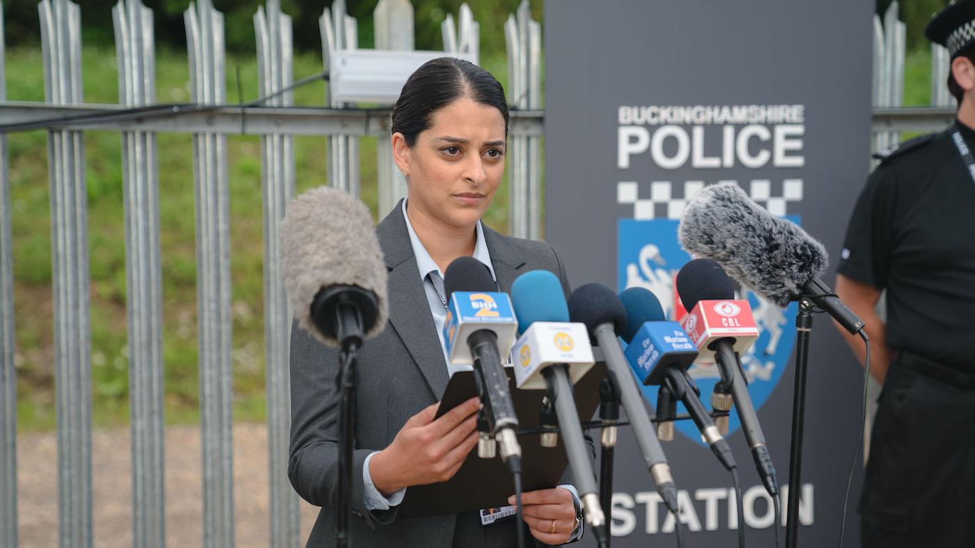 Tanika Malik gives a press conference in front of microphones