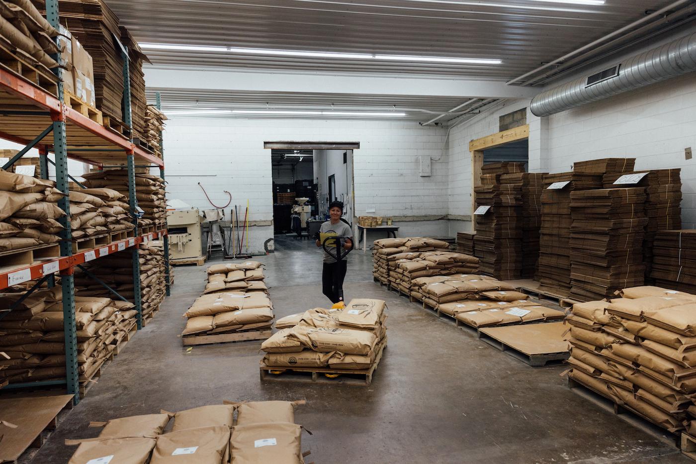 Bre Mathy pulls a pallet with bags of flour on it through a warehouse