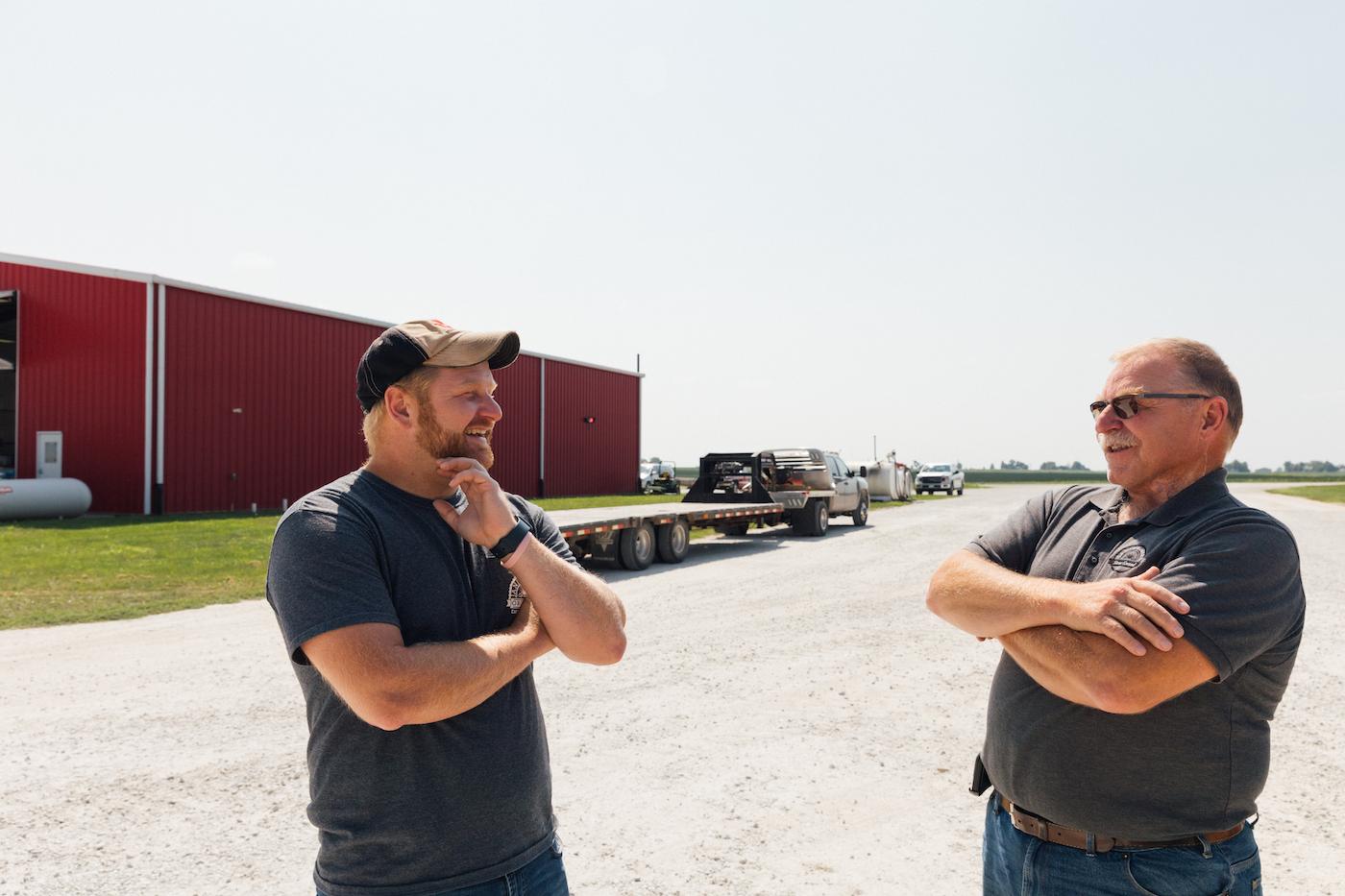 Ross and Harold Wilken laugh and talk with their arms crossed on their farm