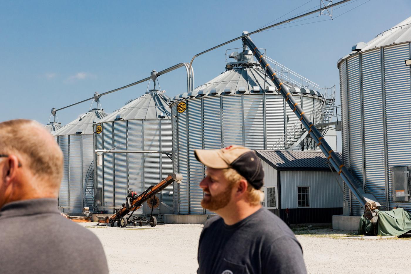 Harold and Ross Wilken stand in front of large grain bins on their farm