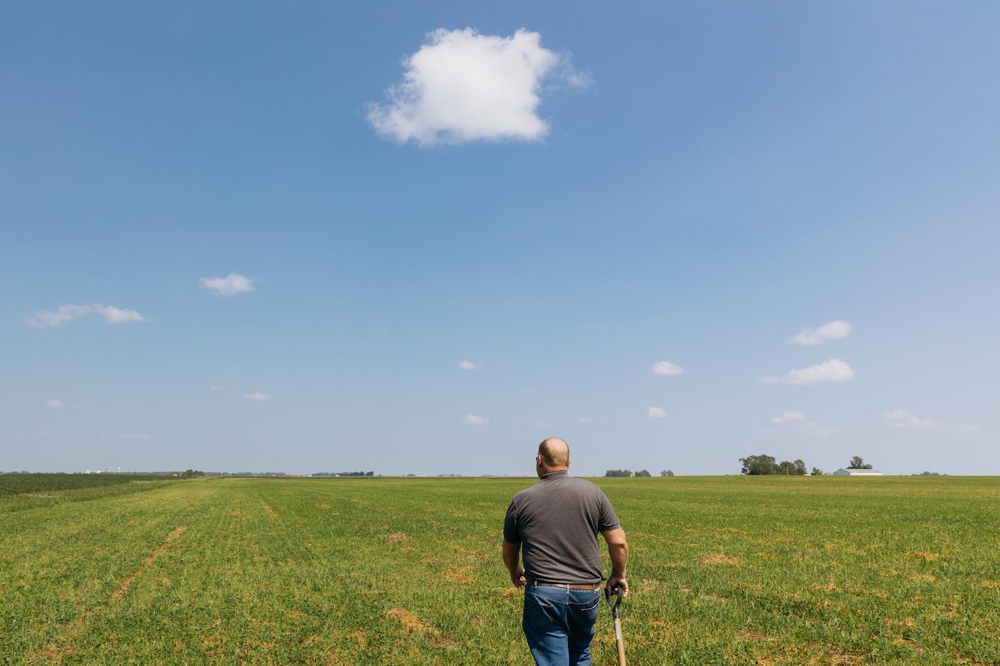 Harold Wilken walks through a field under a blue sky