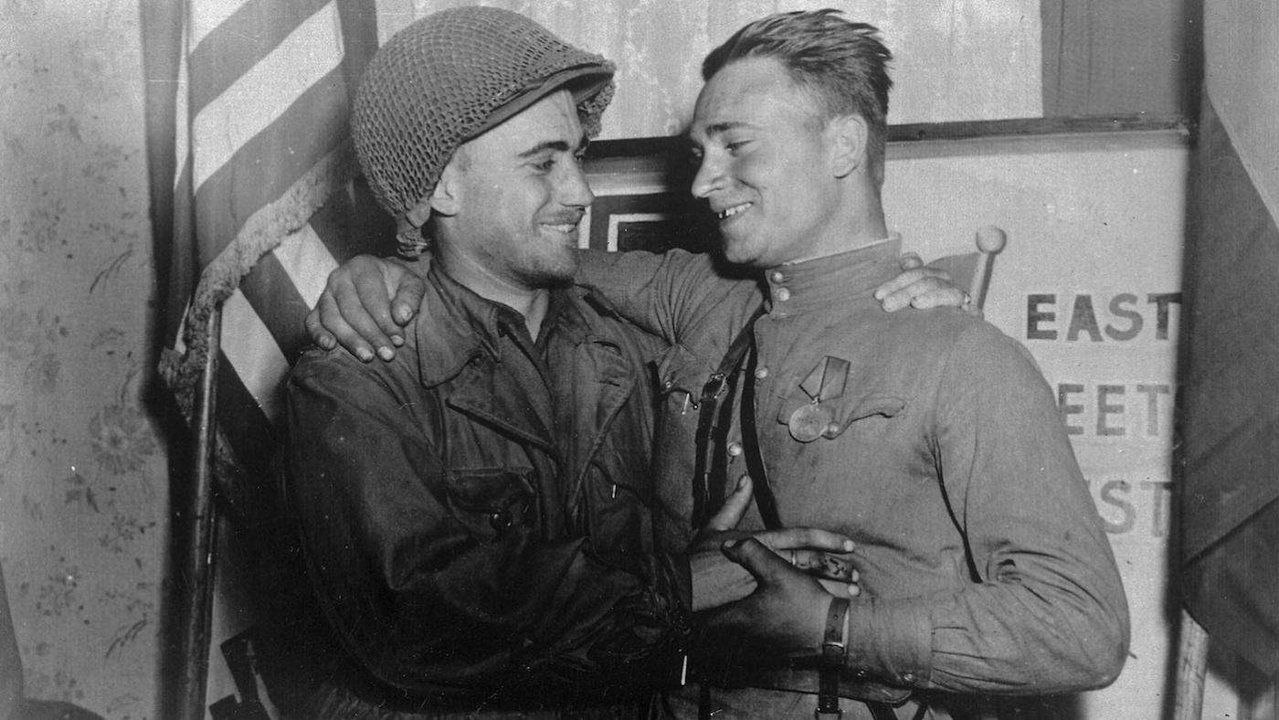 2nd Lt. William Robertson and Lt. Alexander Sylvashko, Red Army, shown in front of sign [East Meets West] symbolizing the historic meeting of the Soviet and American Armies, near Torgau, Germany on Elbe Day. Photo: Pfc. William E. Poulson/U.S. National Archives and Records Administration