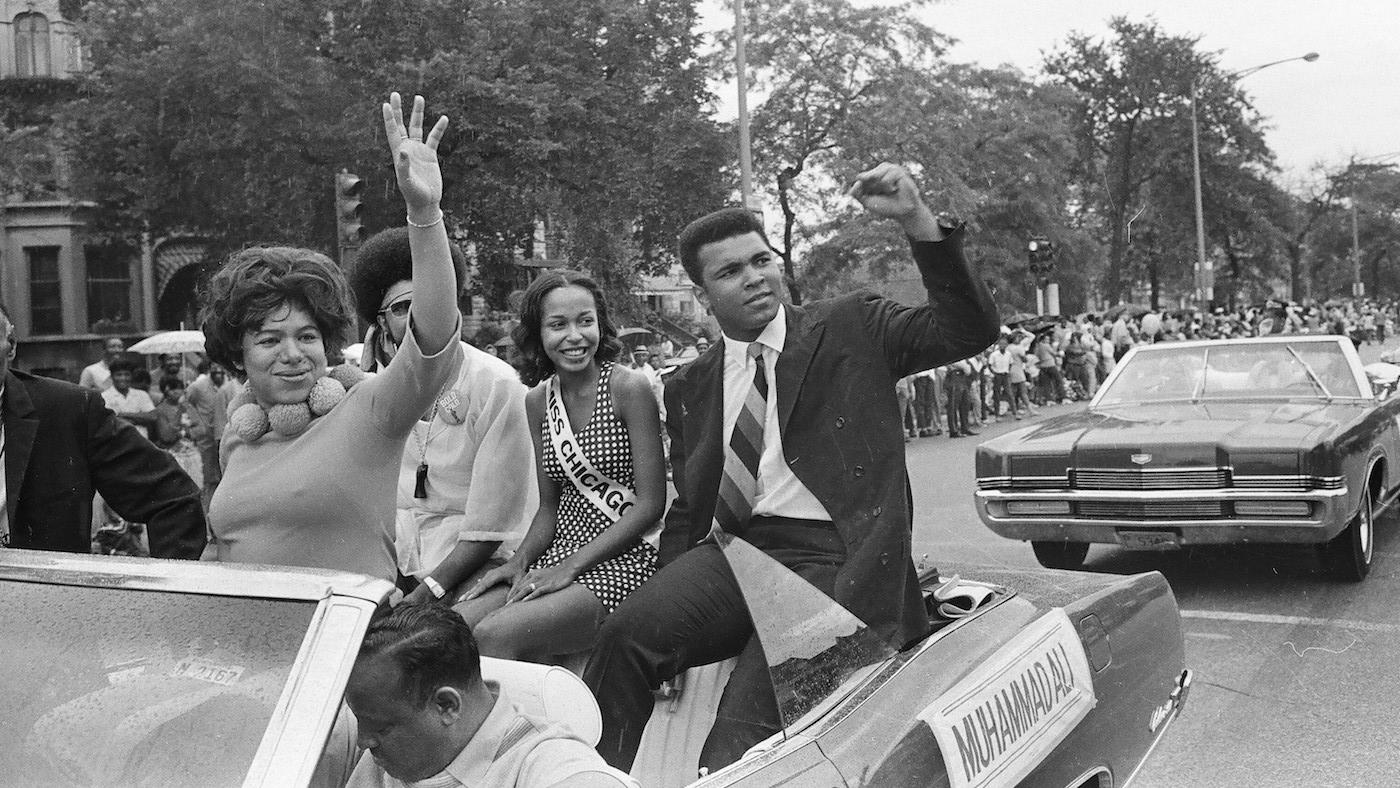 Muhammad Ali sitting in the back of a convertible waving to a crowd during the Bud Billiken Day Parade at 39th Street and Martin Luther King Drive, Chicago, Illinois on August 9, 1969. Photo: ST-40001287-0032, Chicago Sun-Times collection, Chicago History Museum