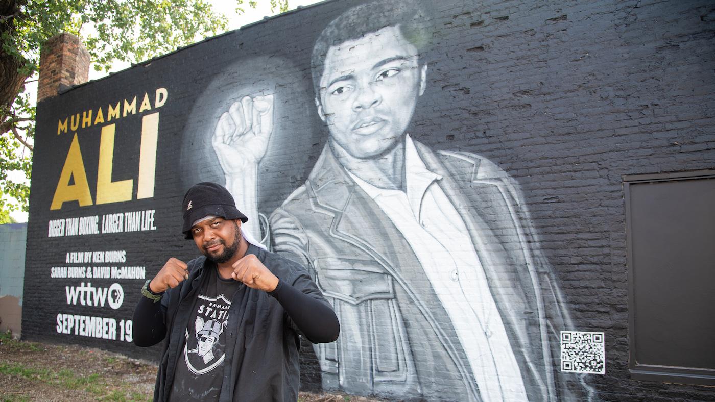 Rahmaan Statik in front of his Muhammad Ali mural. Photo: WTTW/Liz Markel