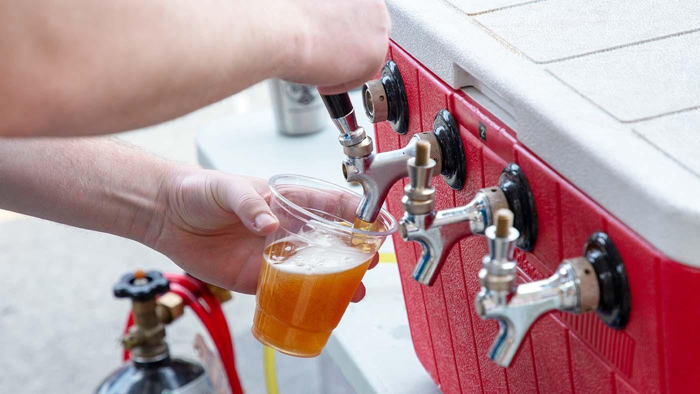 A person's hands pouring a beer out of a tap 