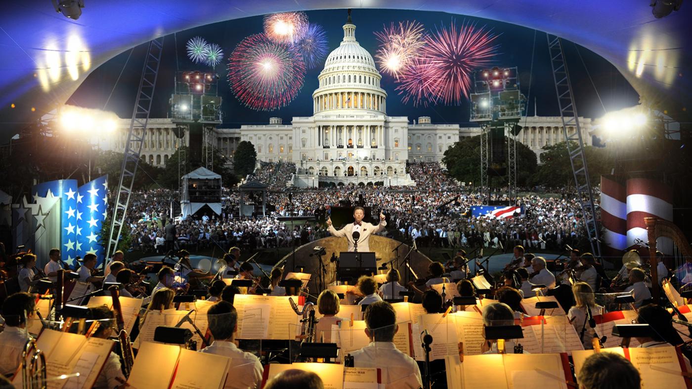 The National Symphony Orchestra performs under the direction of Jack Everly in front of a large crowd before the U.S. Capitol and fireworks