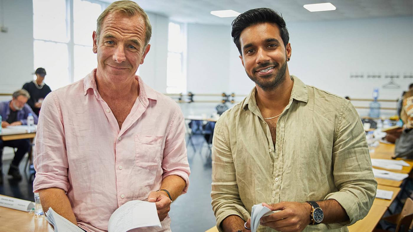 Robson Green and Rishi Nair smile at the camera while holding scripts for Grantchester