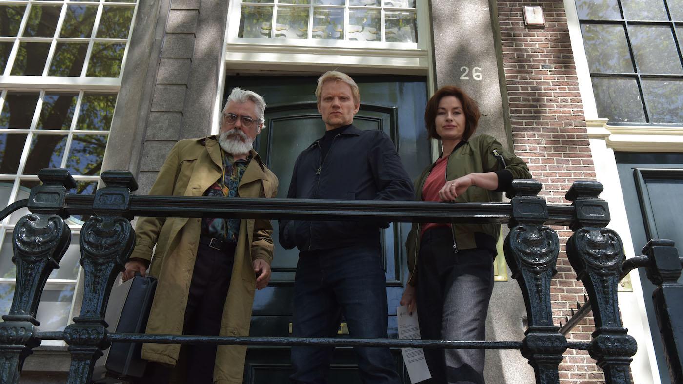 Hendrik, Van der Valk, and Lucienne look over a railing