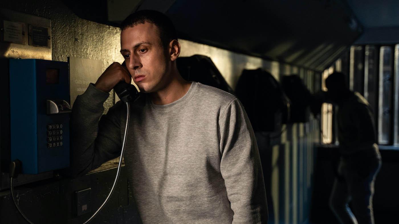 Jay Royce stands in shadows on a phone in prison
