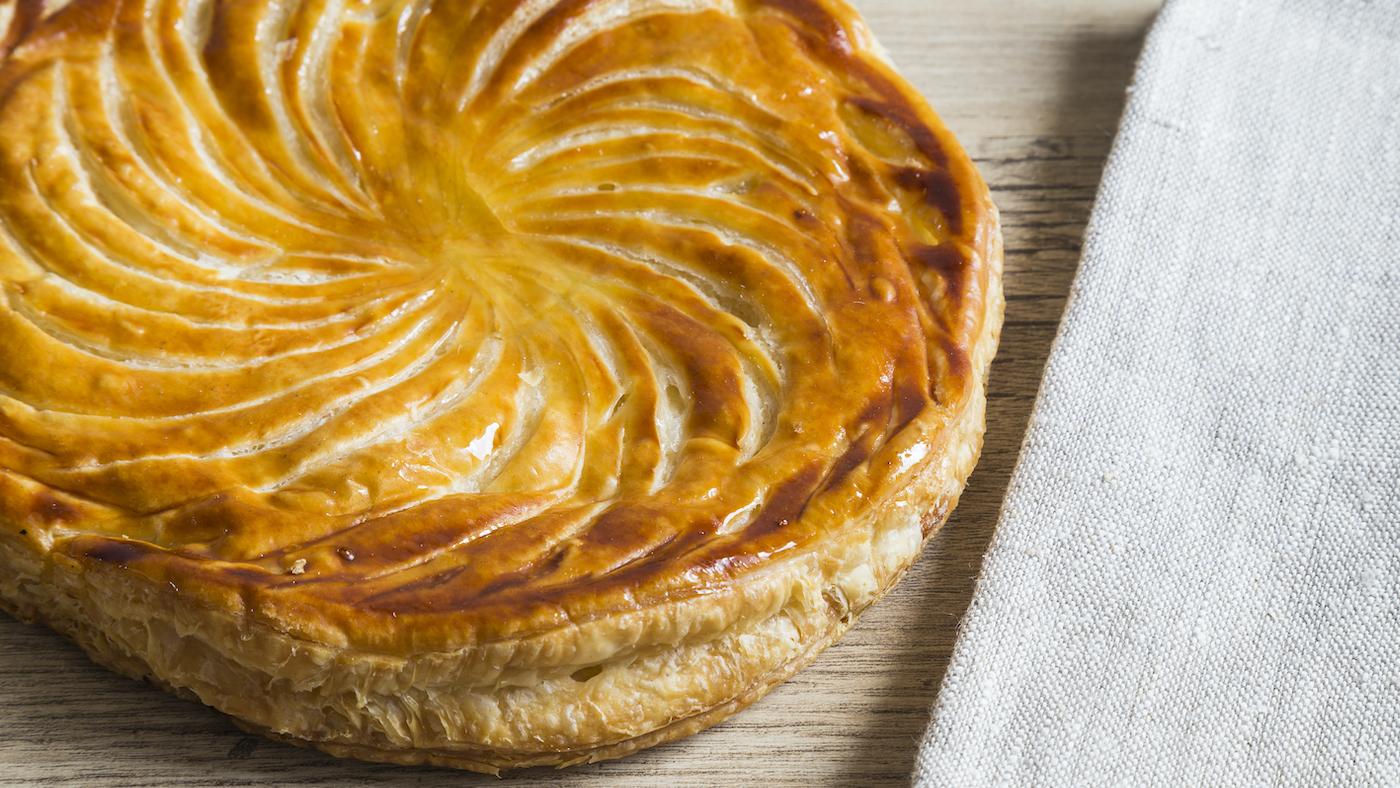A galette des rois next to a napkin on a table