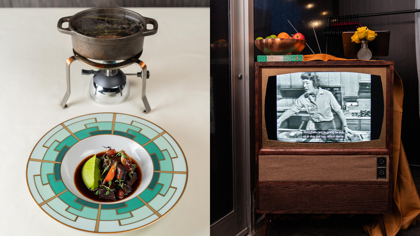 A dish of boeuf bourguignon in front of a small pot on a table next to a TV set playing a Julia Child show in black and white