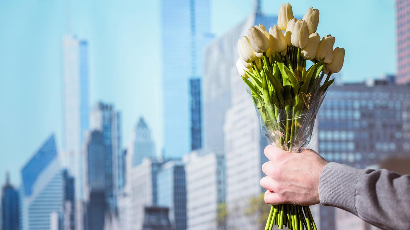 A man holding in his hands a bouquet of white tulips flowers against the background of Chicago skyscrapers