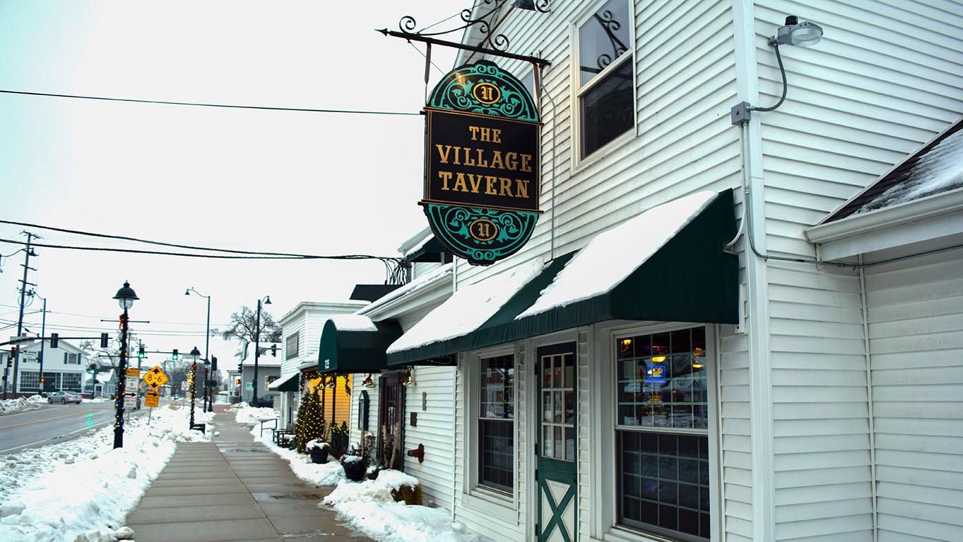 An exterior view of The Village Tavern in Long Grove, pictured in winter with snow on the ground.