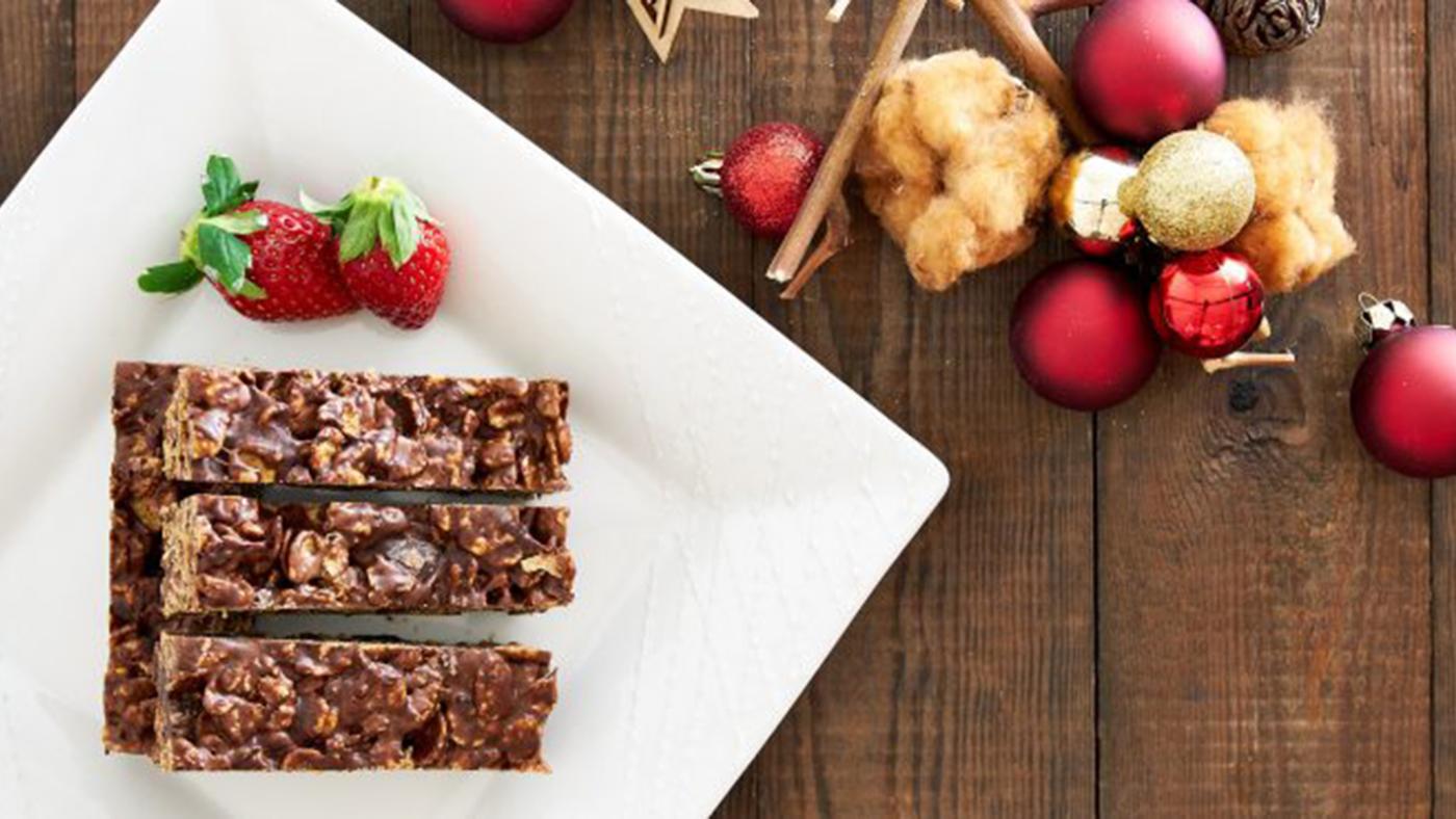 Chocolate cornflake bars on a plate next to strawberries, on a table with decorations