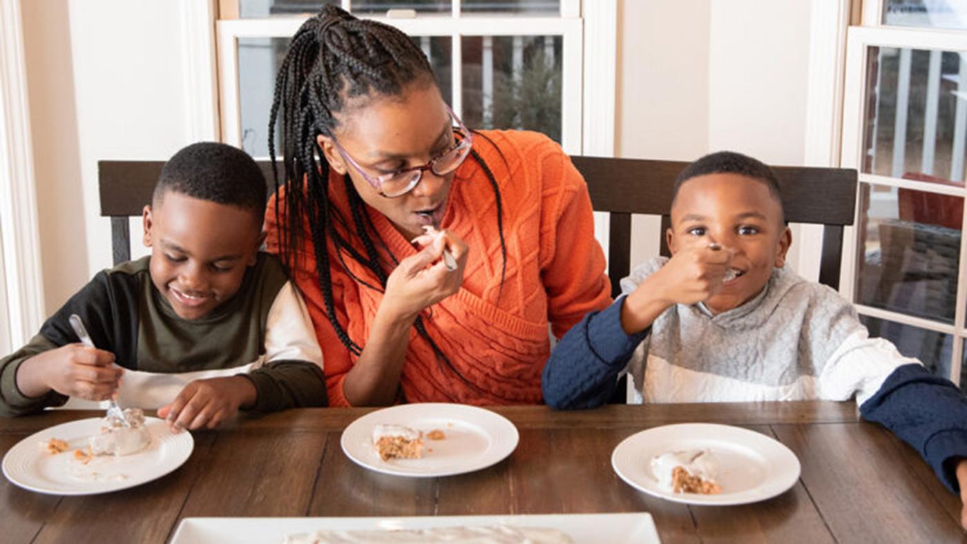 A mom and her children enjoy eating carrot cake at a table