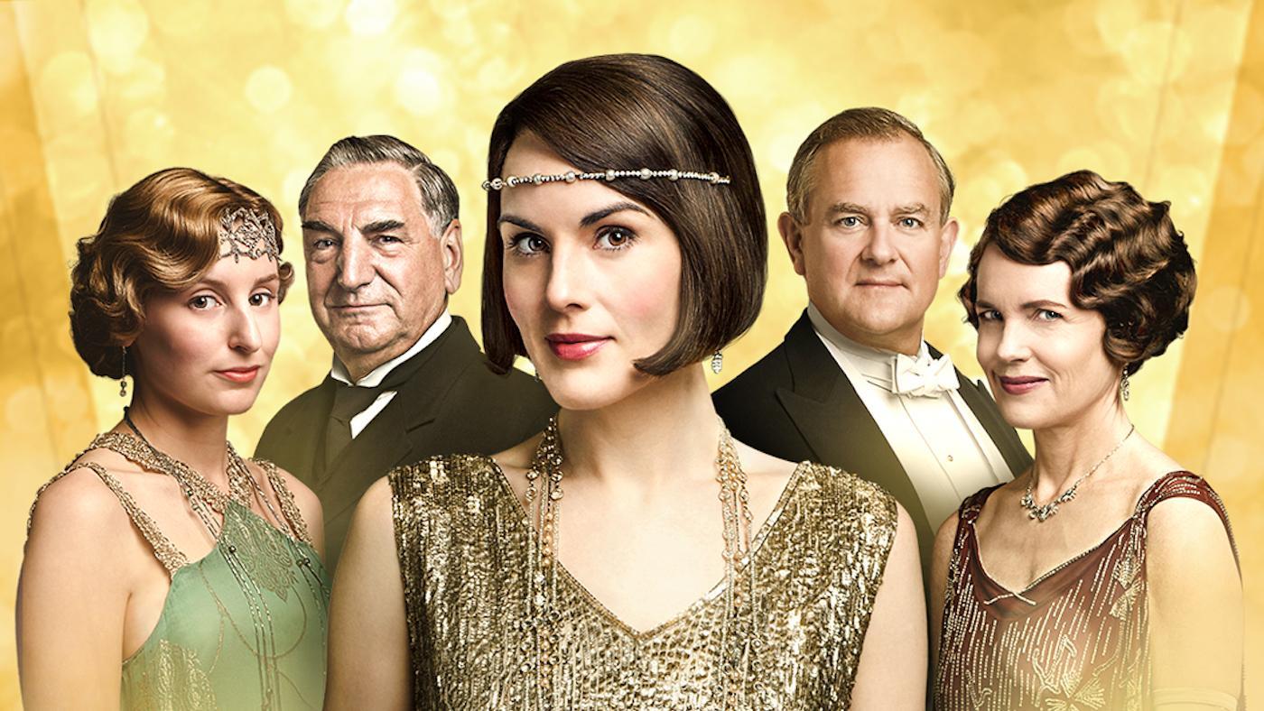 Some of Downton Abbey's cast smiles against a gold backdrop
