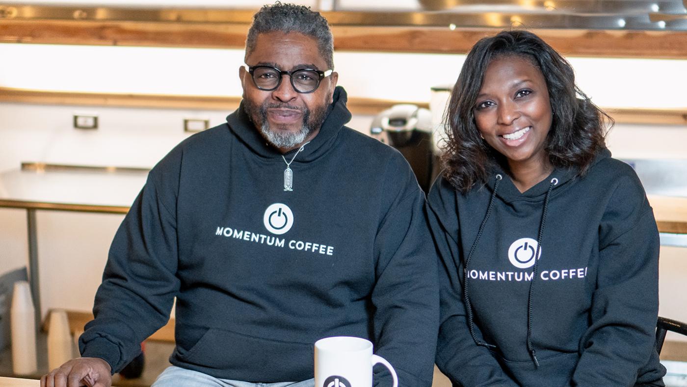 Tracy Powell and Nikki Bravo pose for a photo in sweatshirts branded Momentum Coffee
