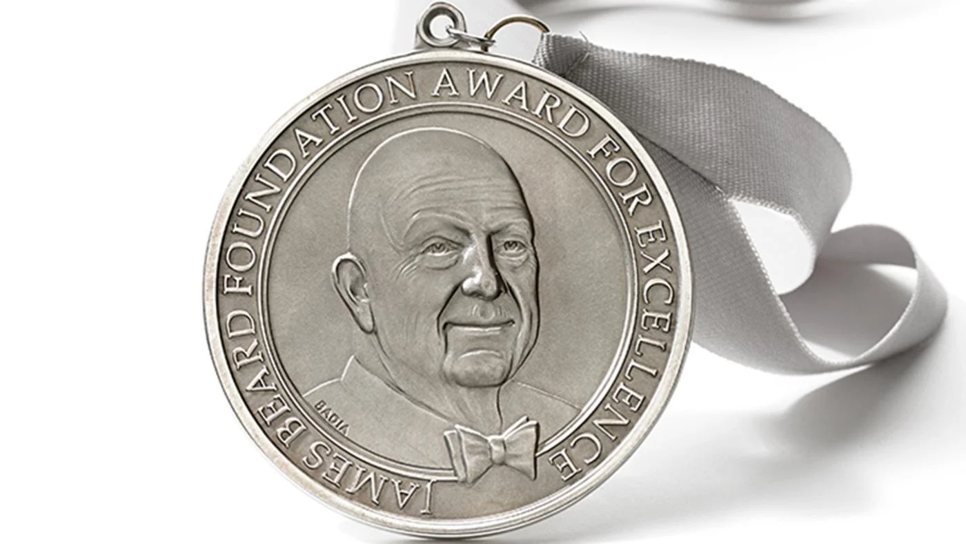 A James Beard Award on a ribbon against a white backdrop