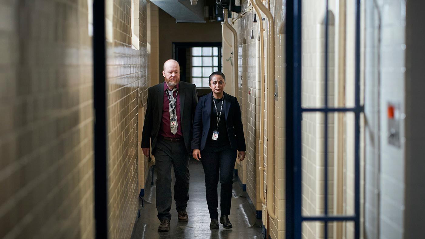 DI Ray and Clive walk down a narrow hallway