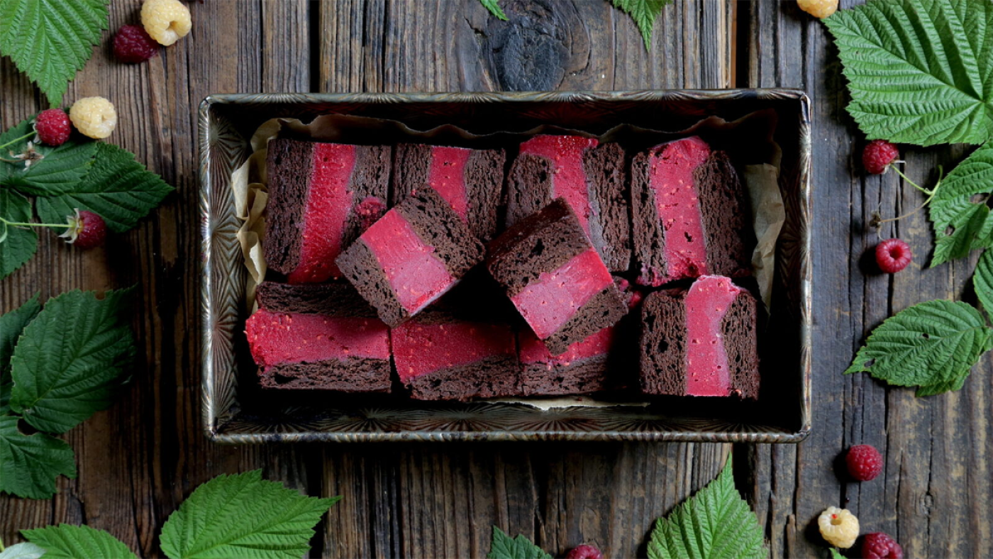 A tray of brownie-raspberry ice cream bars on a table with leaves