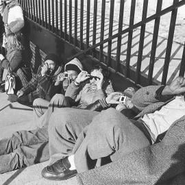 A black and white image of eclipse viewers sitting on the ground and viewing the eclipse through viewing devices at Adler Planetarium in 1979.