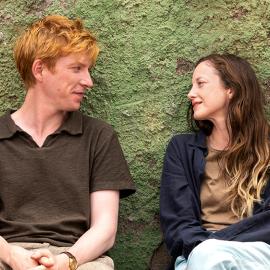 Jack and Alice sit and look at each other in front of a greenish wall