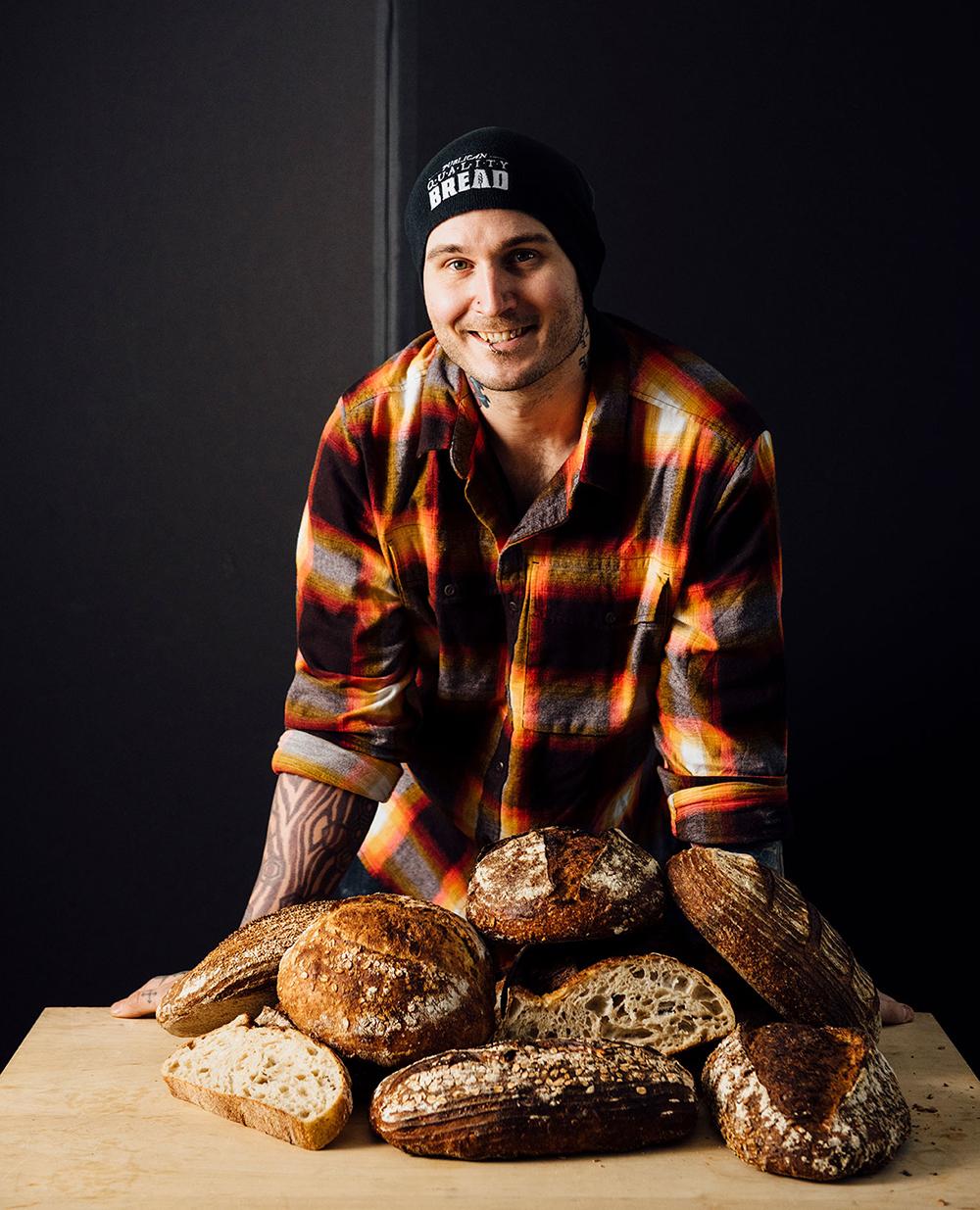 Greg Wade standing in front of several loaves of bread
