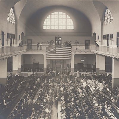Immigrants seated on long benches at Ellis Island. Photo: Courtesy of The New York Public Library