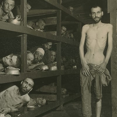 Former prisoners of Buchenwald concentration camp are pictured in the wooden bunks where they slept. Elie Wiesel is pictured in the second row of bunks, seventh from the left, next to the vertical beam. Photo: Courtesy National Archives and Records Administration