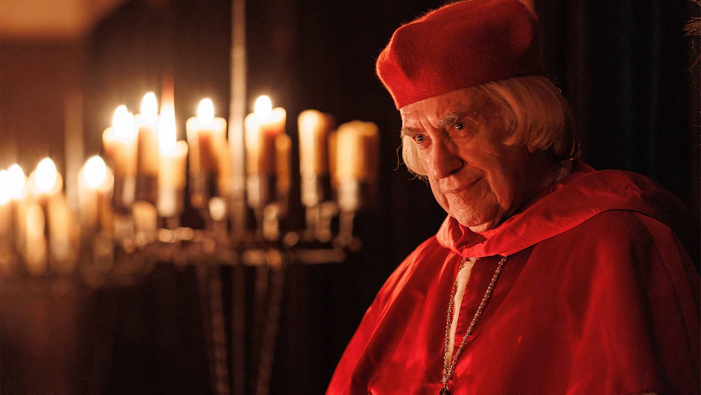 Cardinal Wolsey in red in front of many candles