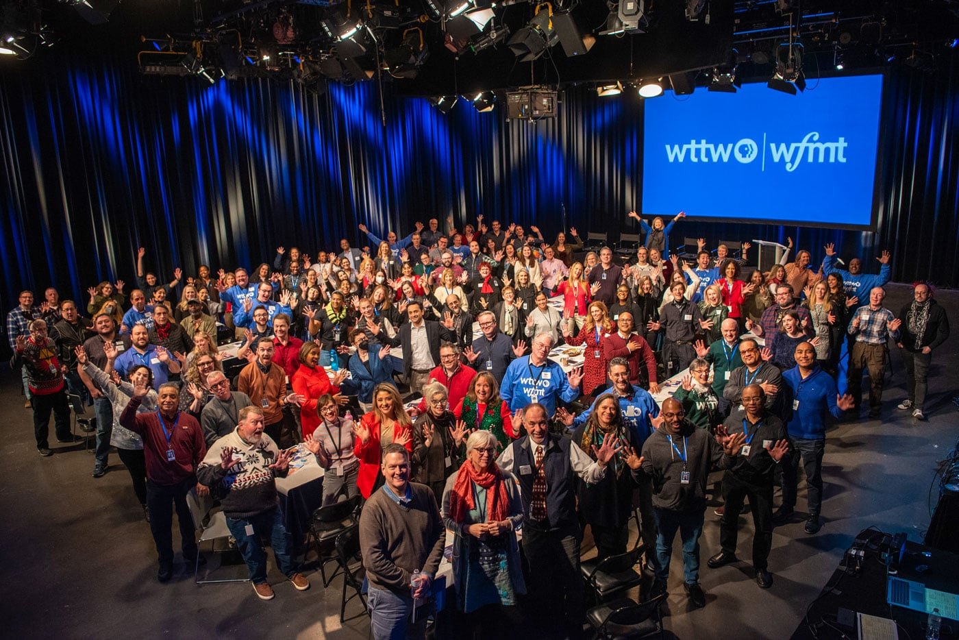 Large group of WTTW and WFMT staff in studio waving at camera